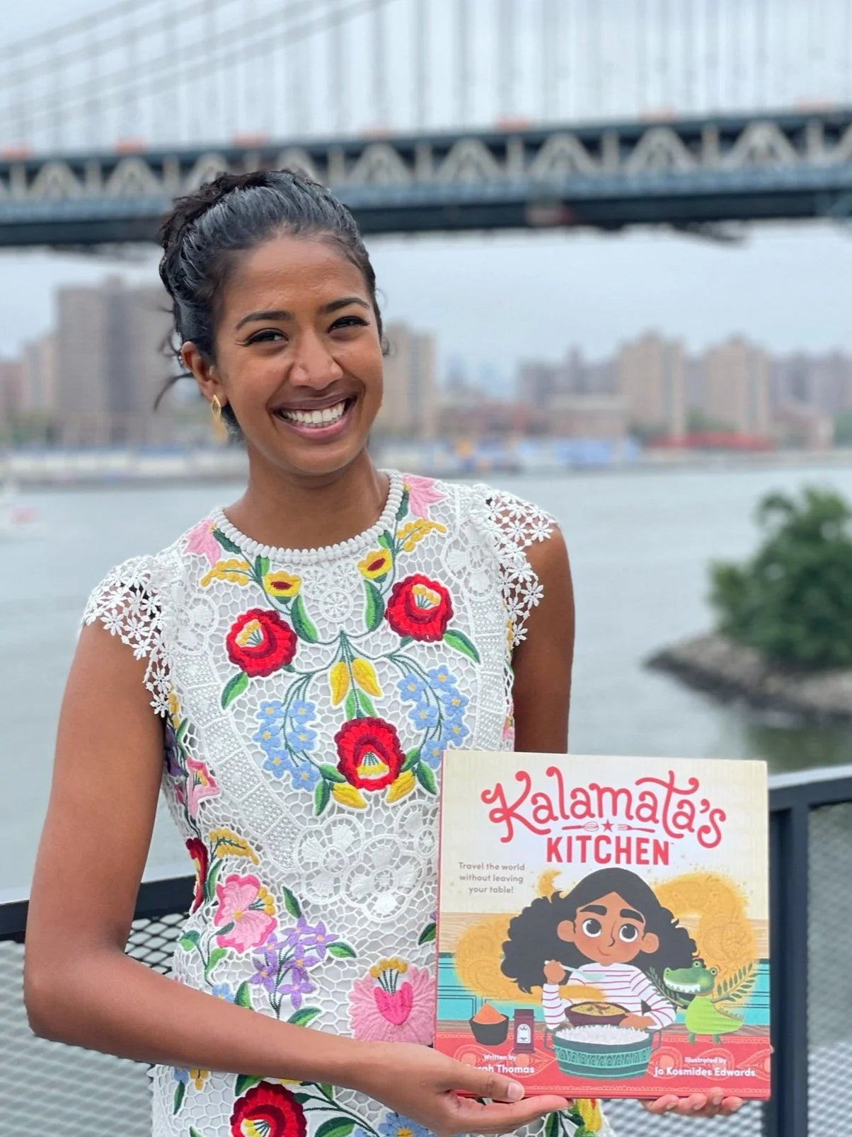 Author Sarah Thomas holding her book titled Kalamata's Kitchen.